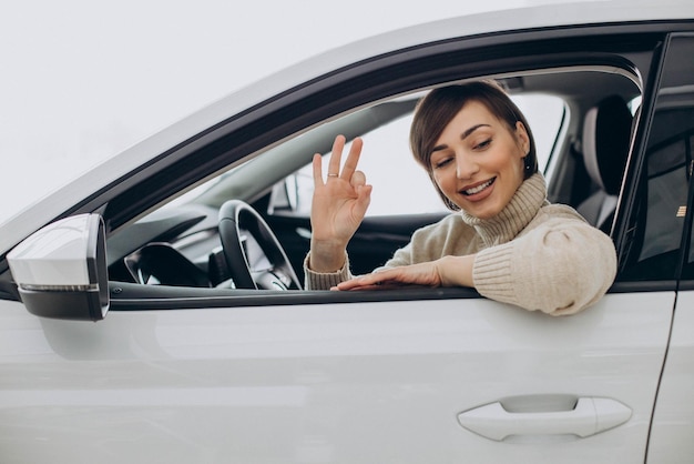 Mujer sentada en un auto en una sala de exposición de autos