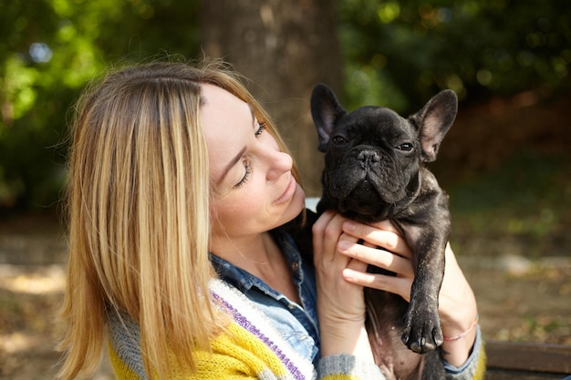 Mujer sentada en un banco con bulldog francés