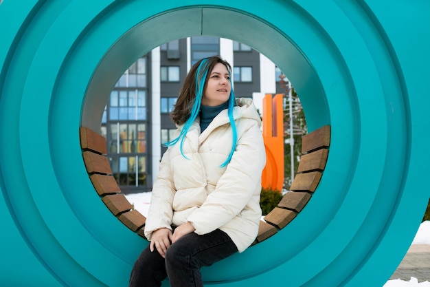 Mujer sentada en un banco frente a una escultura