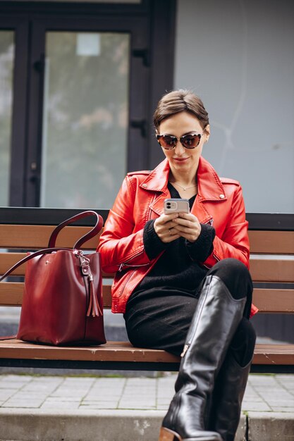 Mujer sentada en un banco y usando teléfono móvil y tomando café