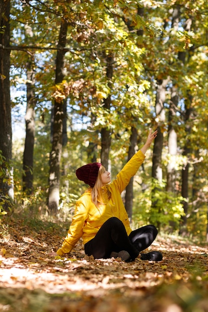 Foto una mujer sentada en el bosque de otoño en un día soleado
