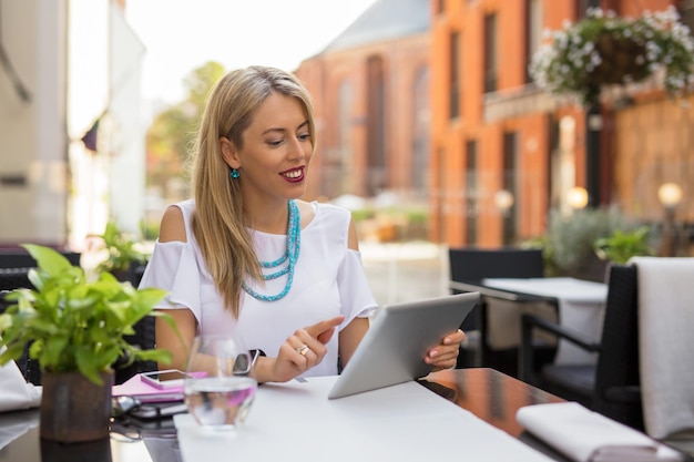 Mujer sentada en un café al aire libre y usando una tableta