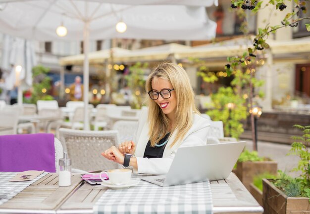 Mujer sentada en un café y usando un reloj de pantalla táctil digital