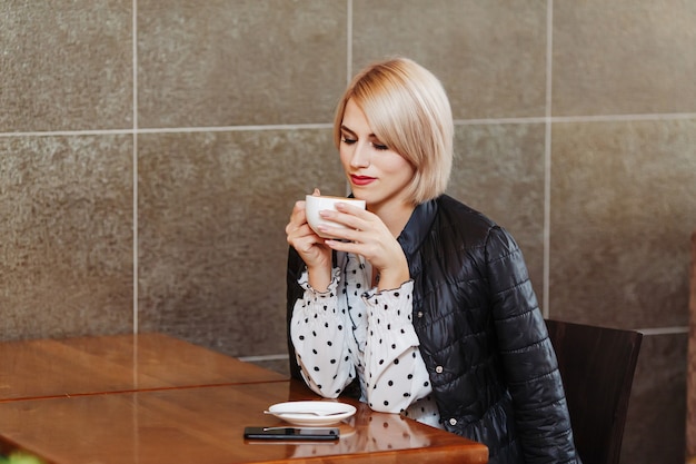 Mujer sentada en la cafetería y tomando café