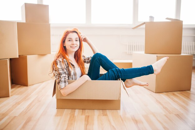 Mujer sentada en caja de cartón, inauguración de la casa. Mudarse a una vivienda nueva