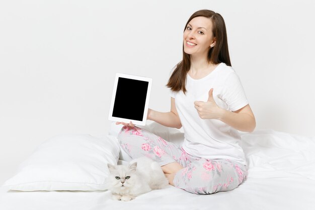 Mujer sentada en la cama con blanco lindo gato persa chinchilla plateado aislado en la pared blanca