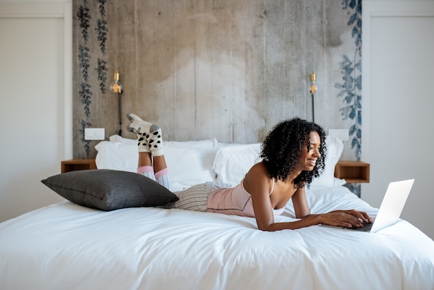 Mujer sentada en la cama en la computadora