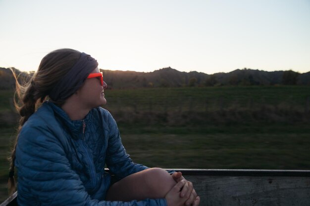 Foto mujer sentada en el campo contra un cielo despejado