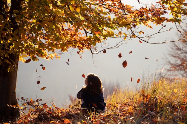 Mujer sentada en el campo durante el otoño