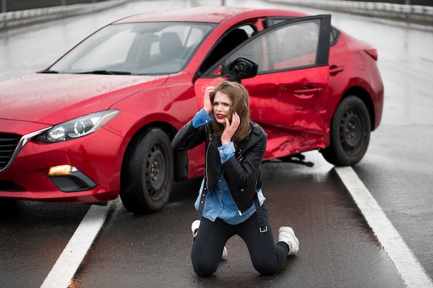 Foto mujer sentada en la carretera después de un accidente automovilístico