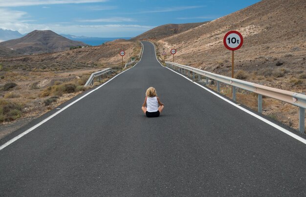 Foto mujer sentada en la carretera