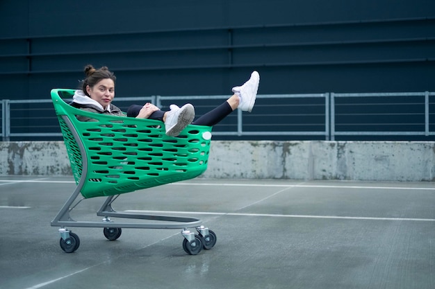 Foto una mujer está sentada en un carrito de compras verde y lleva un zapato blanco.