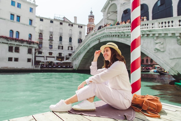 Mujer sentada cerca del puente de rialto en venecia italia mirando el gran canal con góndolas espacio de copia de horario de verano