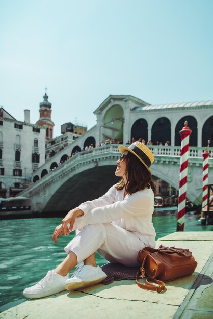 Mujer sentada cerca del puente de rialto en venecia italia mirando el gran canal con góndolas espacio de copia de horario de verano