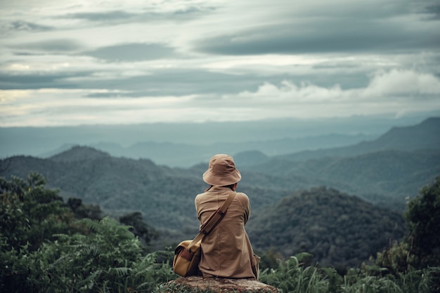 Mujer sentada en la cima de la montaña.