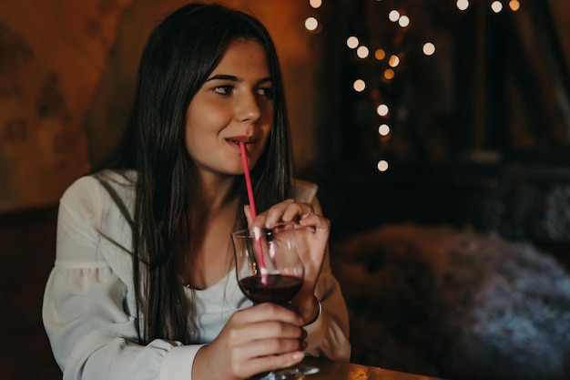 Mujer sentada en un club nocturno y bebiendo un cóctel.