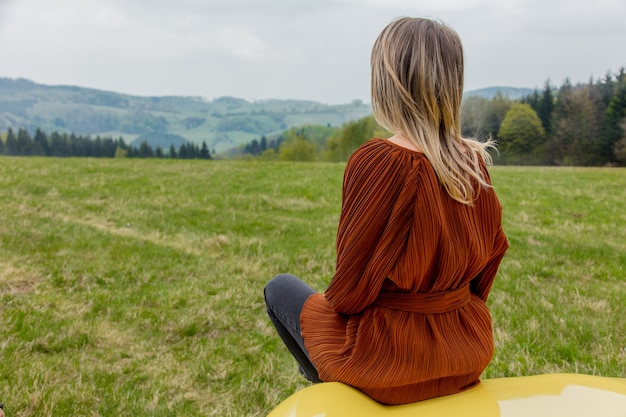 Mujer sentada en un coche en época de vacaciones en las montañas, Polonia. Tiempo de primavera