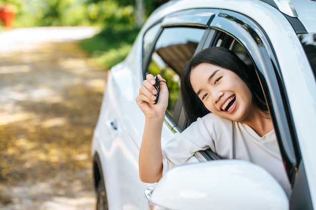 Mujer sentada en el coche y sosteniendo las manos de las llaves del coche fuera del coche