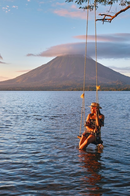 Una mujer sentada en un columpio en el lago durante la puesta de sol en la isla de Ometepe Nicaragua