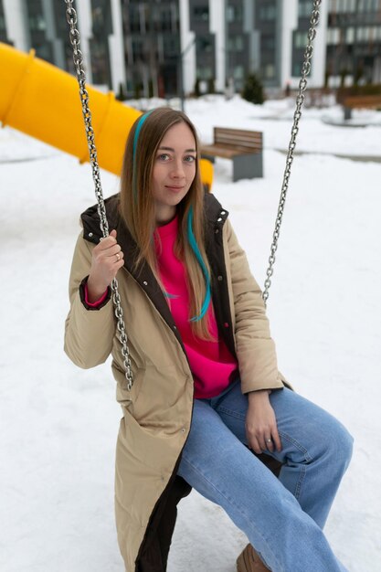 Mujer sentada en un columpio en la nieve