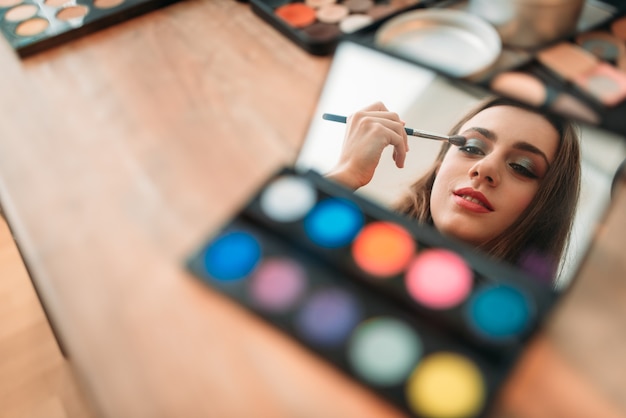 Mujer sentada contra el espejo en el estudio de belleza