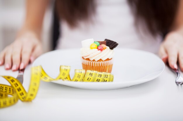 Mujer sentada delante de la placa con deliciosos pasteles de tarta de crema