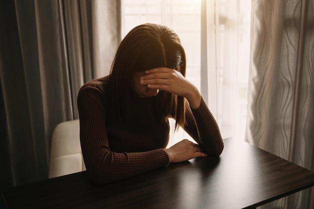 Mujer sentada Depresión De pie junto a la ventana en la mesa de madera y ansiedad Copiar espacio xA