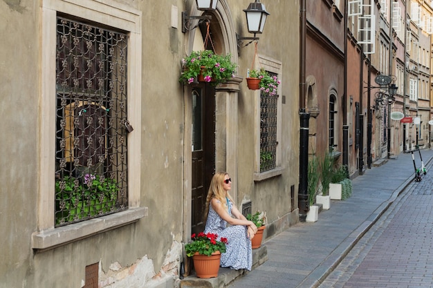 Foto mujer sentada en un escalón en la calle de la ciudad vieja