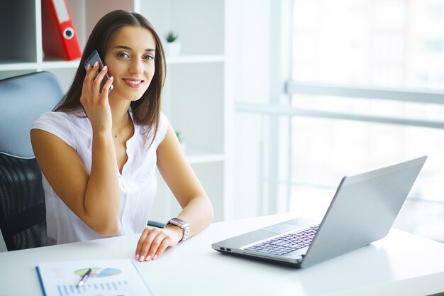 Mujer sentada en el escritorio, trabajando en la computadora portátil en la oficina moderna