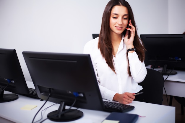 Foto mujer sentada en el escritorio, trabajando en la computadora portátil en la oficina moderna