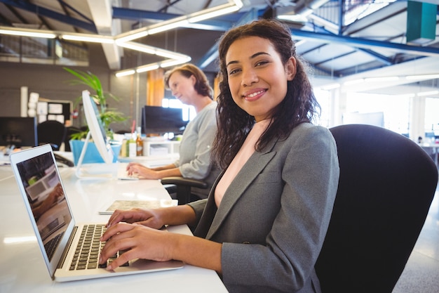 Mujer sentada en el escritorio y trabajando en la computadora portátil