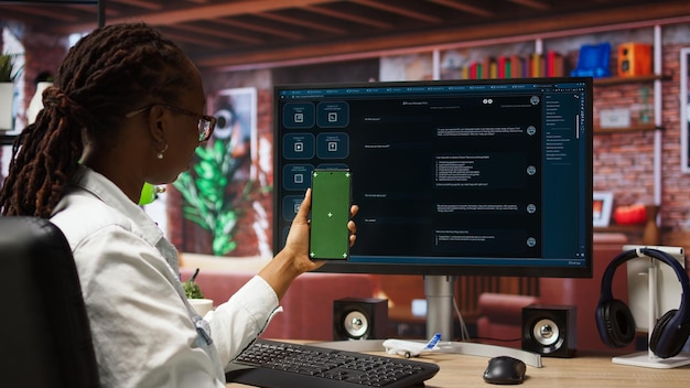 Mujer sentada en un escritorio usando software de chatbot AI LLM y teléfono de pantalla verde