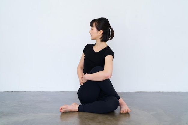 Mujer sentada y haciendo yoga en interiores con ropa negra