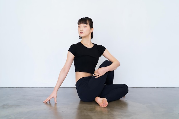 Mujer sentada y haciendo yoga en interiores con ropa negra