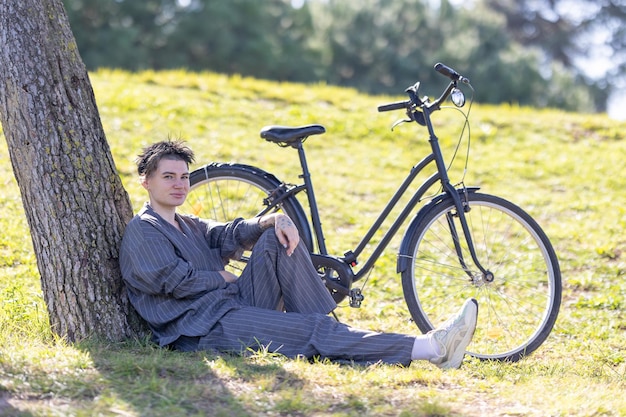 Foto una mujer está sentada en la hierba junto a una bicicleta