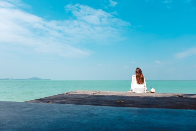 Foto mujer sentada junto al mar