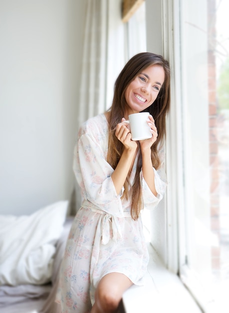 Mujer sentada junto a la ventana bebiendo té