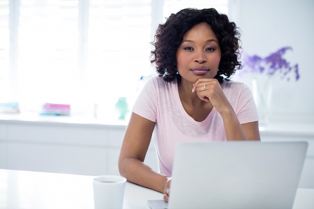 Mujer sentada con laptop y taza de café en la mesa