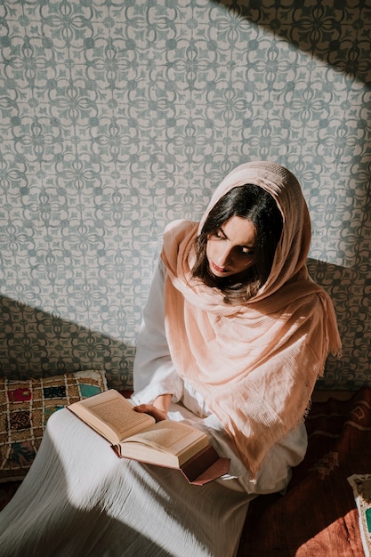 Mujer sentada leyendo en corán