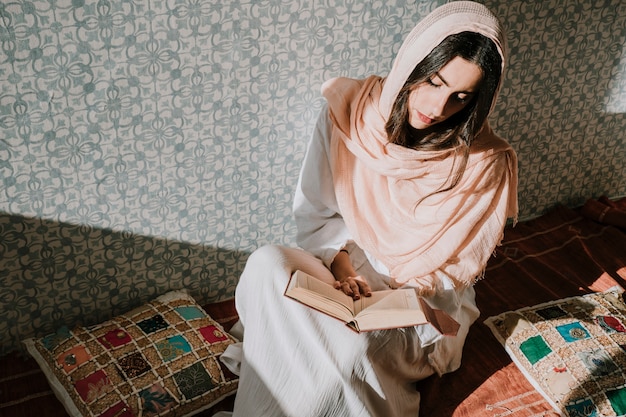 Foto mujer sentada leyendo en corán