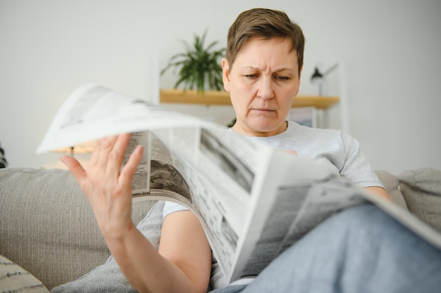 Mujer sentada leyendo el periódico en casa