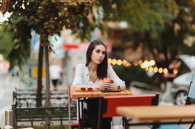 Mujer sentada en una mesa en la calle. Noche cálida ciudad. Foto de alta calidad