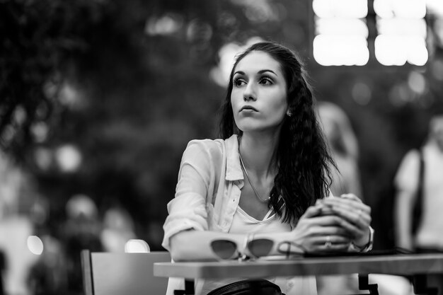 Mujer sentada en una mesa en la calle. Noche cálida ciudad. Foto de alta calidad