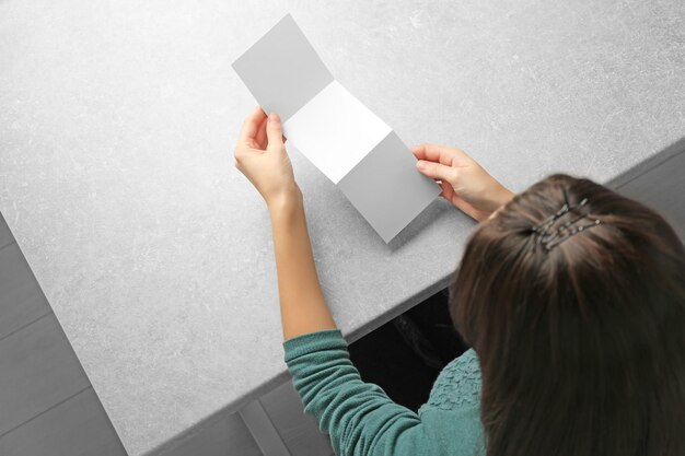 Mujer sentada a la mesa con folleto en blanco