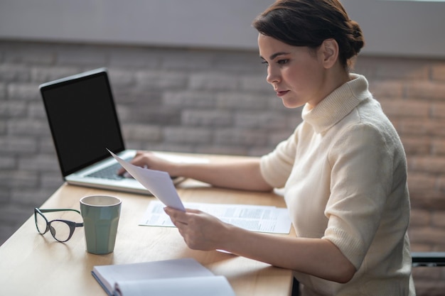 Una mujer sentada en la mesa de la oficina y trabajando.