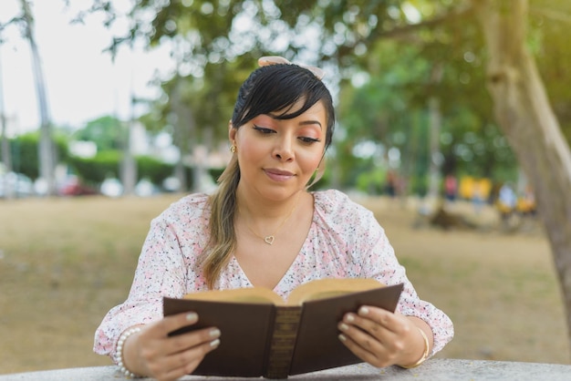 Mujer sentada en una mesa del parque leyendo un libro Día mundial del libro Concepto de lectura