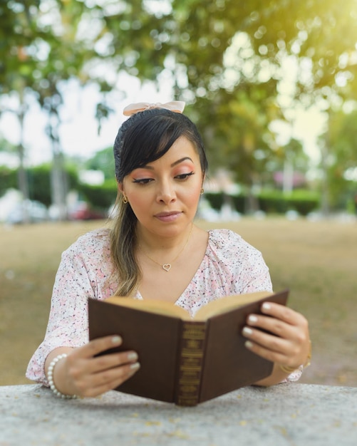 Foto mujer sentada en una mesa del parque leyendo un libro día mundial del libro concepto de la lectura.