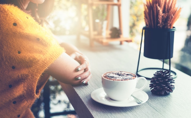 Foto mujer sentada en una mesa con una taza de café