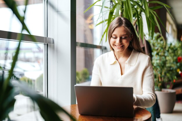 Mujer sentada en la mesa usando una computadora portátil