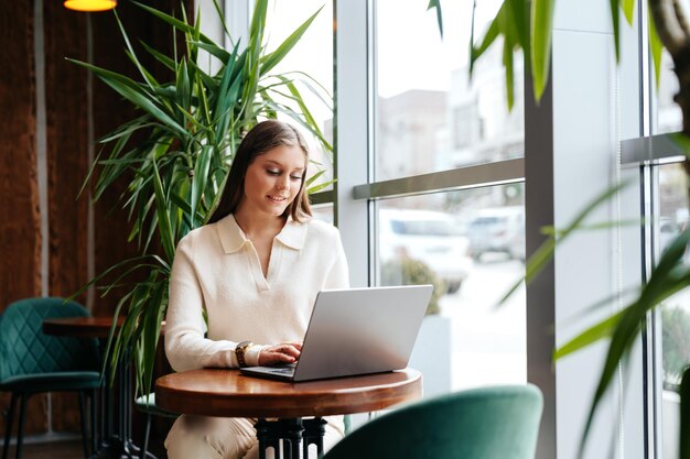 Mujer sentada en la mesa usando una computadora portátil